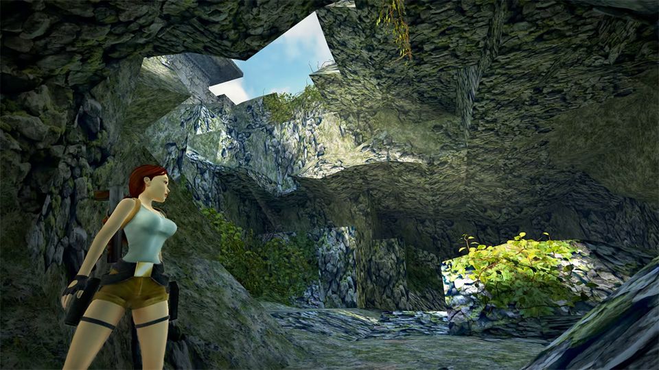 Lara Croft staat in een begroeide rotsgrot met een opening naar de blauwe lucht.