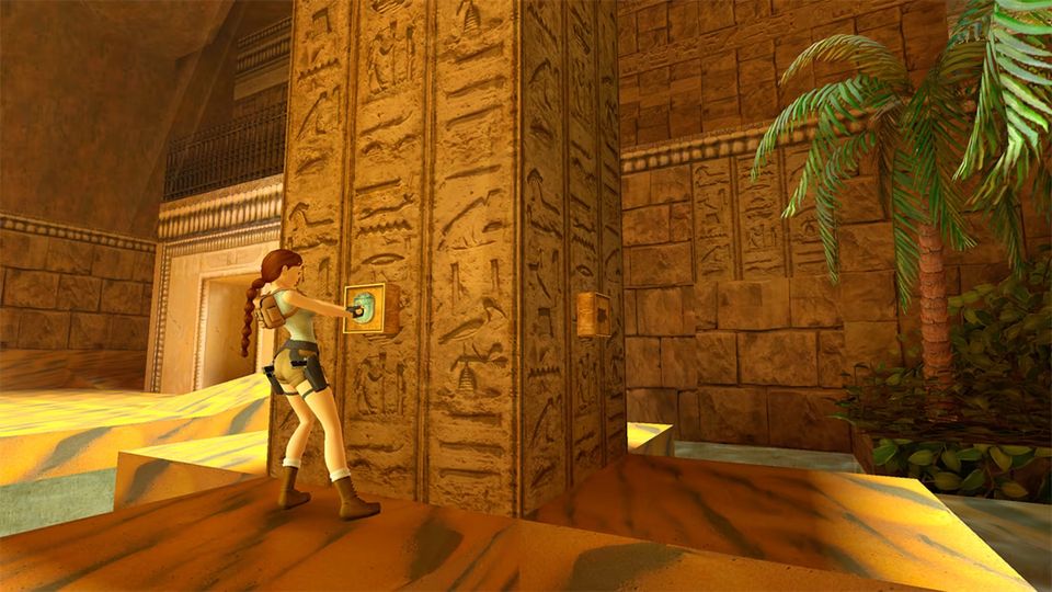 Lara Croft drukt op een schakelaar in een Egyptische tombe met hiërogliefen op de pilaren.