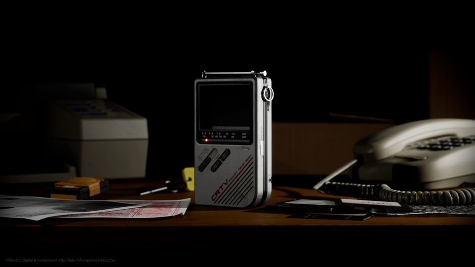 Een draagbare CRTV-televisie op een donker bureau naast een oude telefoon in Silent Hill: Townfall.